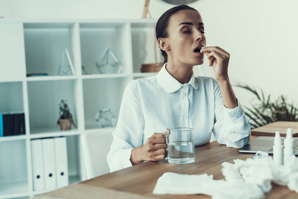 Young Sick Woman in White Shirt Sitting in Office.Healthcare Concept. Modern Office. Sick Worker. Healthcare in Office. Wooden Table. Digital Device. Laptop on Desk. Young Woman in Office. - 写真・画像