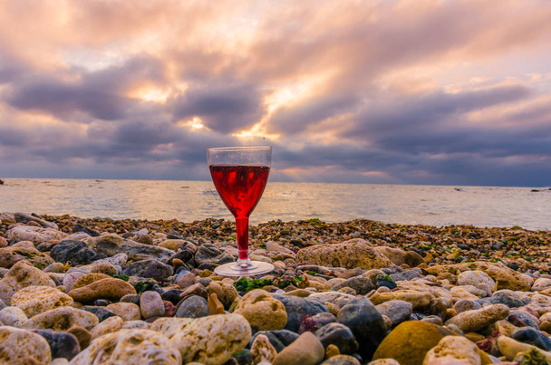 Glass with wine on the sea beach during the sunset - Fotografie, Obrázek