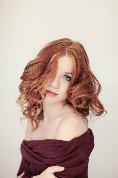 Portrait of a beautiful young woman with long red curly hair and perfect make up, cozy red winter sweater, can be used as background - Photo, Image