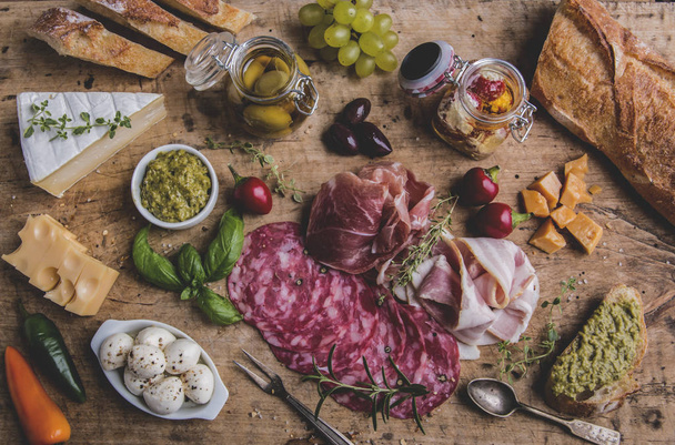 Wooden board with prosciutto, salami,bacon and cheese mozzarella ,brie,olives,pesto - Photo, Image