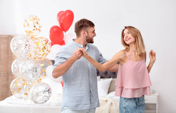 Young couple with air balloons in bedroom. Celebration of Saint Valentine's Day - Φωτογραφία, εικόνα