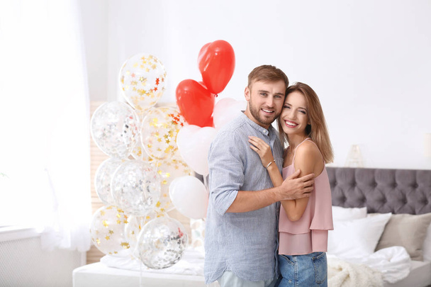 Young couple with air balloons in bedroom. Celebration of Saint Valentine's Day - Фото, изображение