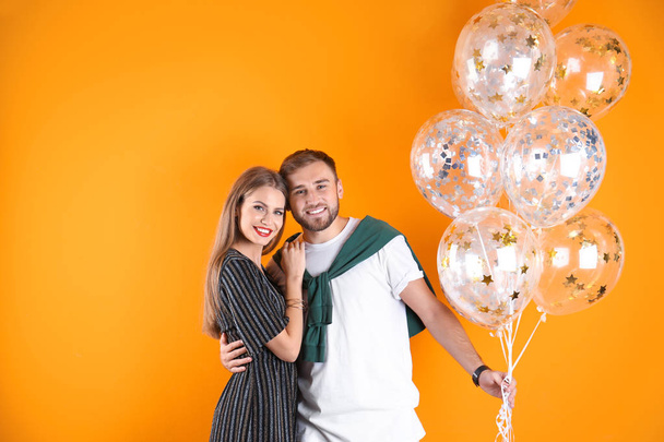 Young couple with air balloons on color background - Valokuva, kuva