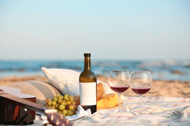 Blanket with food, wine and guitar on beach. Romantic picnic for couple - Fotoğraf, Görsel