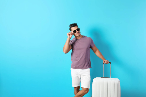 Young man with suitcase on color background - Foto, Bild