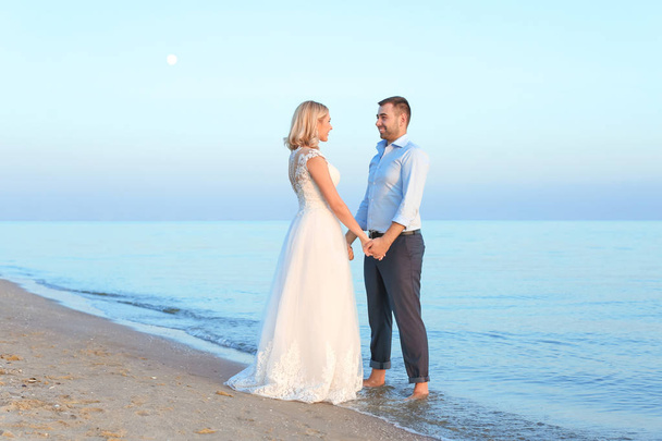 Wedding couple holding hands together on beach - Photo, Image
