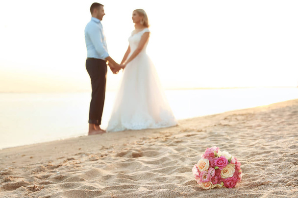 Bouquet and wedding couple on beach. Space for text - Zdjęcie, obraz