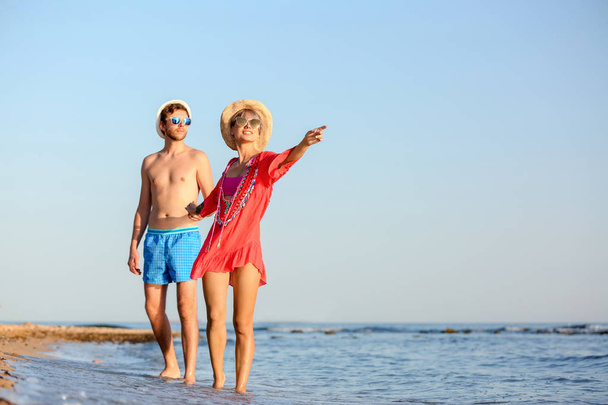 Happy young couple walking together on beach. Space for text - Foto, Imagem