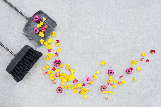 Varredura flores secas e pétalas de rosa no pátio do jardim, com escova e espanador, sobre fundo piso de concreto. Mudança de estações
. - Foto, Imagem