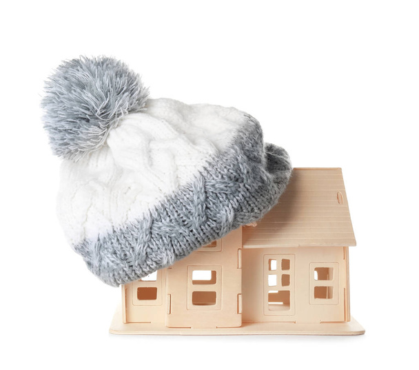 白い背景に、屋根の上のニット帽子の家モデル。加熱コンセプト - 写真・画像