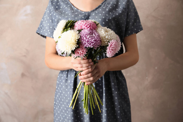 Woman holding beautiful aster flower bouquet against color background - Φωτογραφία, εικόνα