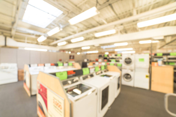 Blurred background retail store with rows of home appliances equipments. Defocused washing machines, electric and gas dryers, stacked laundry center, refrigerators, microwaves, ovens on display. - Photo, Image