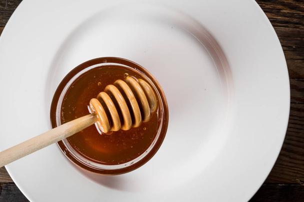 Honey Pot on Edge of Empty Plate with honey off center - Фото, изображение