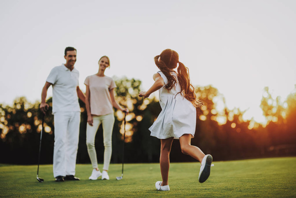 Happy Young Family Relax on Golf Field in Summer. Relaxing in Golf Club. Sports in Summer. Outdoor Fun in Summer. Family Fun Concept. Healthy Lifestyle Concept. Little Girl. Green Grass. - Foto, afbeelding