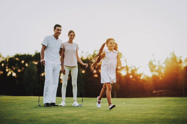 Happy Young Family Relax on Golf Field in Summer. Relaxing in Golf Club. Sports in Summer. Outdoor Fun in Summer. Family Fun Concept. Healthy Lifestyle Concept. Little Girl. Green Grass. - Photo, image