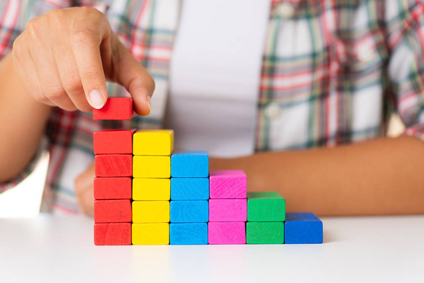 Concept van het gebouw van Stichting succes. Vrouwen hand zetten kleurrijke houten blokken in de vorm van een trap - Foto, afbeelding