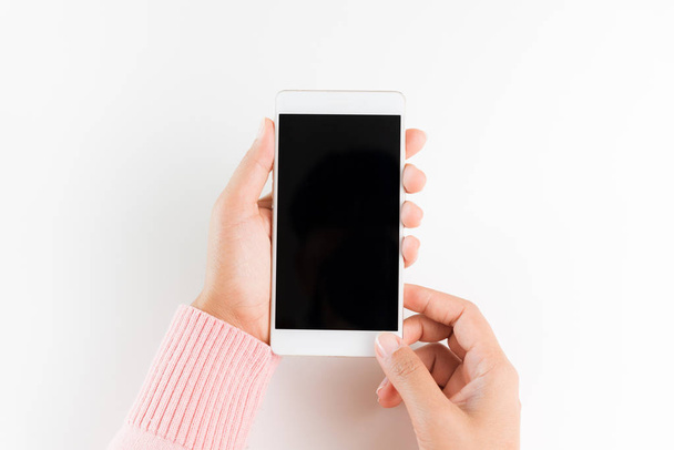 Woman hand holding white mobile phone smartphone on white table background. - 写真・画像