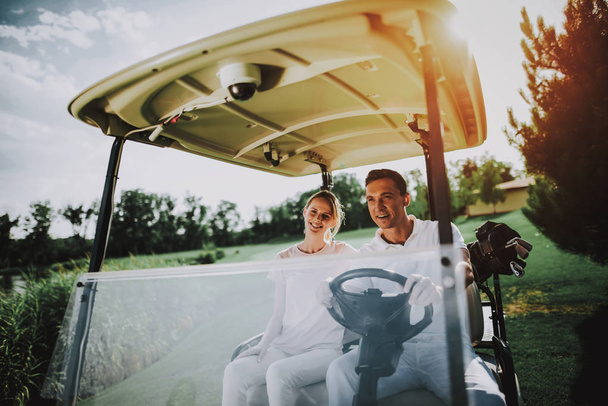 Happy Young Couple in White Cart on Golf Field. Young Family. Golf Club. Sports in Summer. Vehicle on Field. Outdoor Fun in Summer. Driver with Car. Healthy Lifestyle Concept. Couple on Vacation. - Foto, Imagem