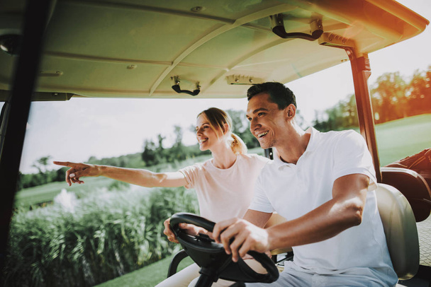 Happy Young Couple in White Cart on Golf Field. Young Family. Golf Club. Sports in Summer. Vehicle on Field. Outdoor Fun in Summer. Driver with Car. Healthy Lifestyle Concept. Couple on Vacation. - Foto, imagen