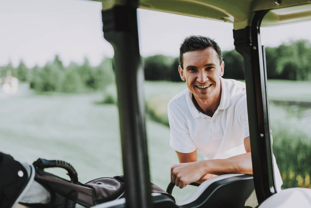 Young Man in White Shirt using Cart on Golf Field. Happy Young Man. Driver with Car. Healthy Lifestyle Concept. Golf Club. Sports in Summer. Vehicle on Field. Family Holiday. Outdoor Fun in Summer. - Photo, Image