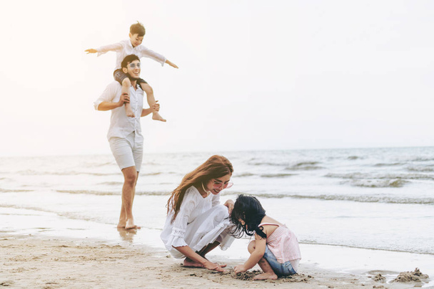 Happy family of father, mother and kids goes vacation on a tropical sand beach in summer. - Photo, Image