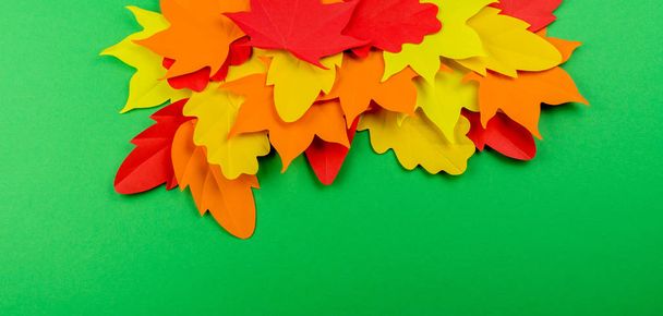 Leaves of paper autumn. Red, yellow and orange leaves. Place for recording. Green background. - Photo, image