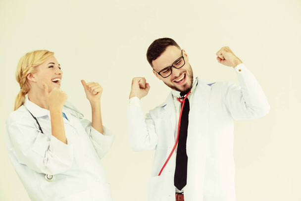 Счастливый успешный врач празднует победу в больничном кабинете с другим врачом, стоящим рядом с ней для успеха лечения пациентов
. - Фото, изображение