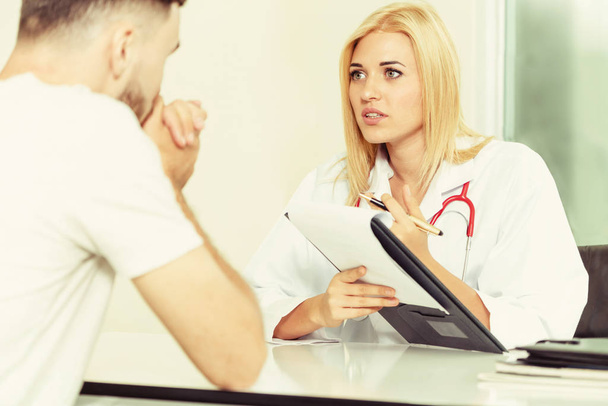 Женщина-врач говорит и осматривает пациента-мужчину в больничном кабинете. Здравоохранение и медицинское обслуживание
. - Фото, изображение