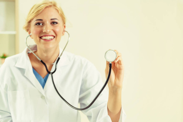 Jeune femme médecin pointant stéthoscope à blanc. Concentration sélective à la main des médecins. Concept de soins médicaux
. - Photo, image