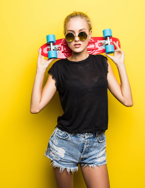 Fashion pretty cool girl with skateboard over colorful orange background - Foto, immagini