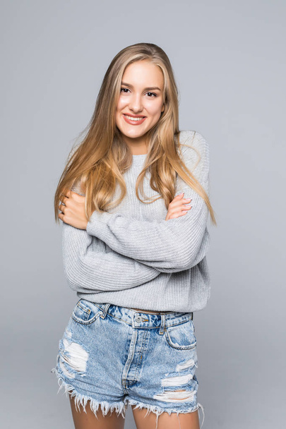 Portrait of a cheerful young woman smiling with arms crossed on gray background - Photo, image