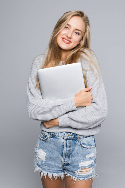 Portrait of happy surprised woman standing with laptop isolated on gray background - Valokuva, kuva