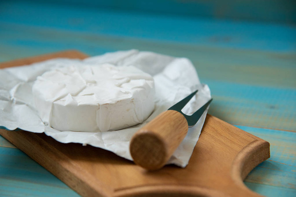 cheese camembert or brie on blue wooden background - 写真・画像