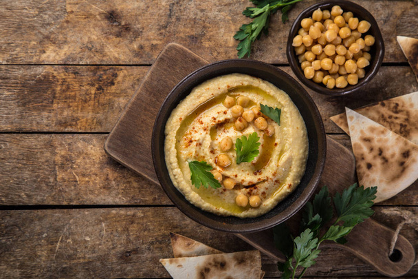 healthy homemade chickpea hummus with olive oil and smoked paprika, wooden background, top view, copy space - Photo, image
