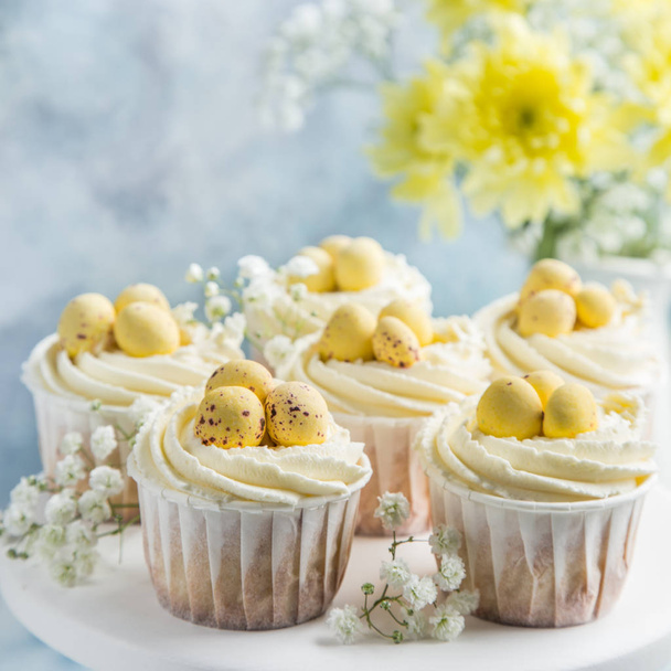 Easter cupcakes decorated with cream cheese frosting and candy eggs, selective focus - 写真・画像