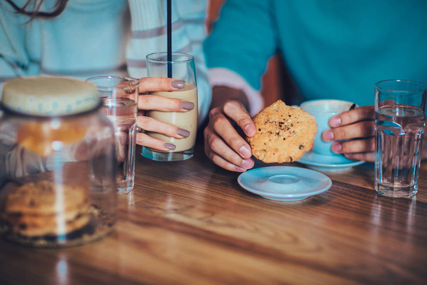 Coffee and cookie in cafe, hands of couple closeup - 写真・画像