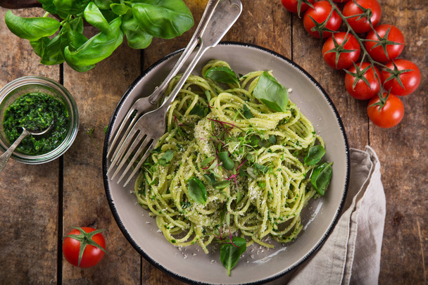 spaghetti pasta with basil pesto sauce, parmesan cheese and microgreens, wooden background, top view, - Фото, изображение