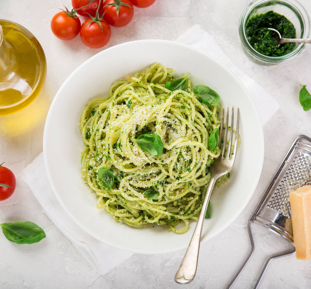 spaghetti pasta with basil pesto sauce and parmesan cheese on white bowl, top view, square image - Foto, Bild