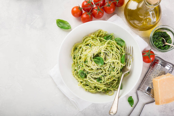 spaghetti pasta with basil pesto sauce and parmesan cheese on white bowl, top view, copy space - Foto, Imagen