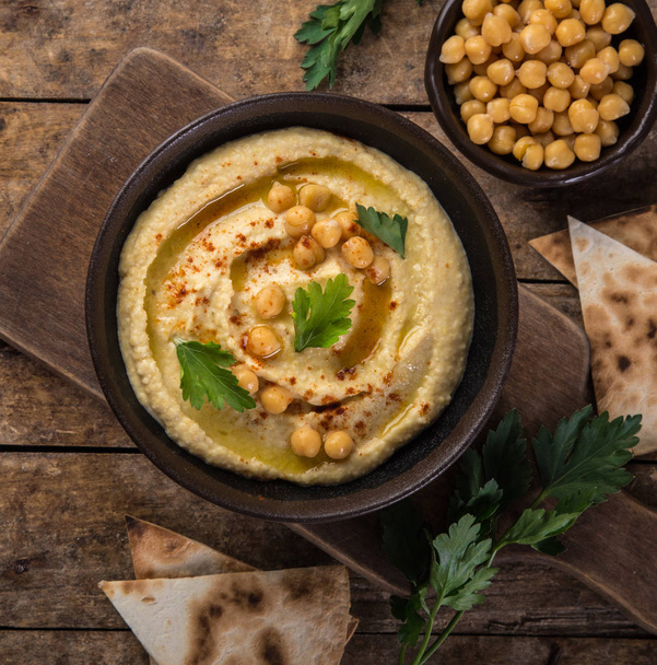 healthy homemade chickpea hummus with olive oil and smoked paprika, wooden background, top view, square image - Zdjęcie, obraz