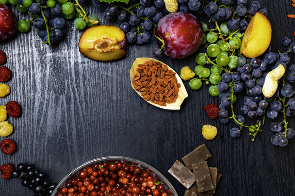 food for your health. Brain boosting health food background border with nuts, fruit, chocolate, goji, raspberrys, grapes. Food high for vitamins, minerals, antioxidants and anthocyanins. Space for text - Photo, Image