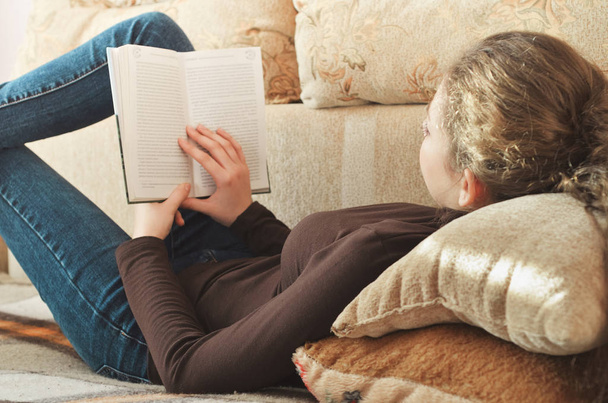 Young beautiful girl reading a book on the couch - Foto, Imagem