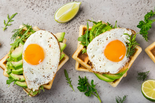 savory waffles with avocado, arugula and fried egg for breakfast, top view - 写真・画像
