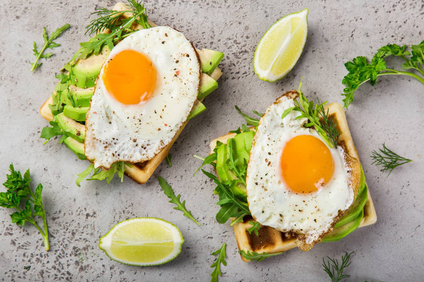 savory waffles with avocado, arugula and fried egg for breakfast, top view - Foto, Imagem