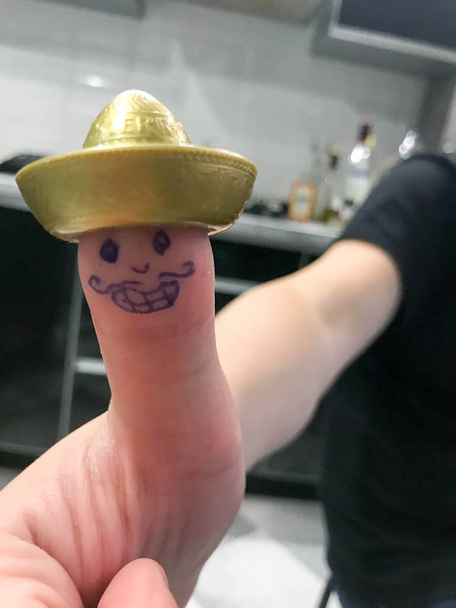 Thumb, finger Mexican in gold hat sombrero with painted cheerful cheerful face with mustaches and eyes - Photo, Image