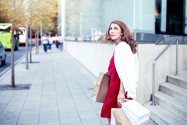 Junge Frau mit Einkaufstüten geht aus dem Geschäft - Foto, Bild