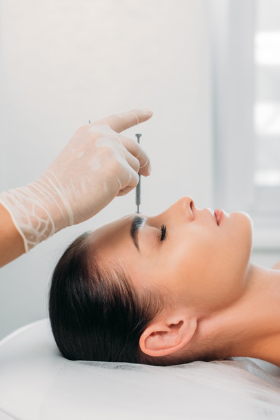 osittainen näkemys kosmetologista laittamassa neulaa naisten otsaan akupunktiohoidon aikana kylpyläsalongissa
 - Valokuva, kuva