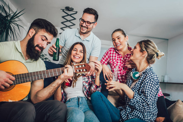 Grupo de jovens amigos felizes se divertindo e bebendo cerveja em casa interior
 - Foto, Imagem