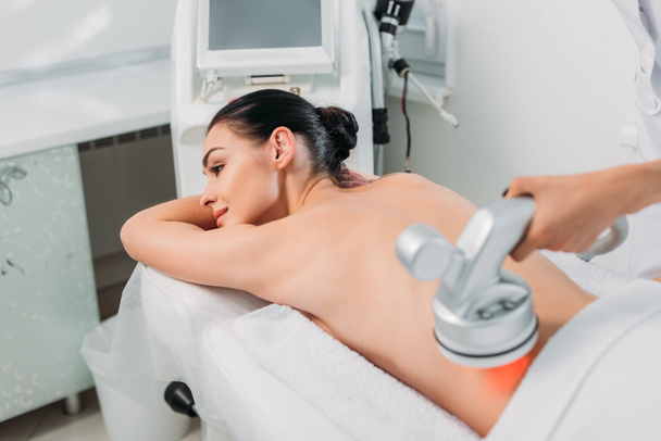 mujer en la mesa de masaje recibiendo masaje eléctrico hecho por el cosmetólogo en el salón de spa
 - Foto, imagen