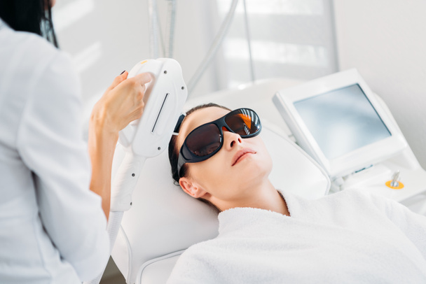 koruyucu gözlük güzellik spa salonda uzmanı tarafından yapılan lazer epilasyon alma kadında - Fotoğraf, Görsel
